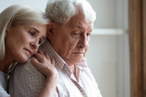 Older man being hugged by his adult daughter