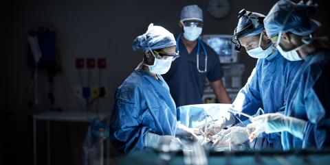 A group of surgeons are operating on a patient in an operating room